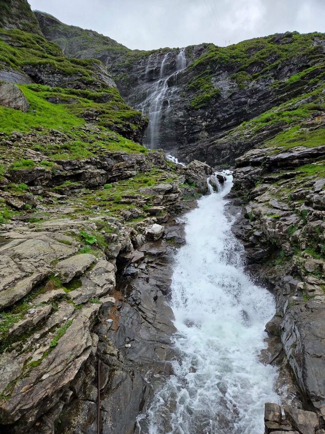 A waterfall that drops down a rock face into a white stream